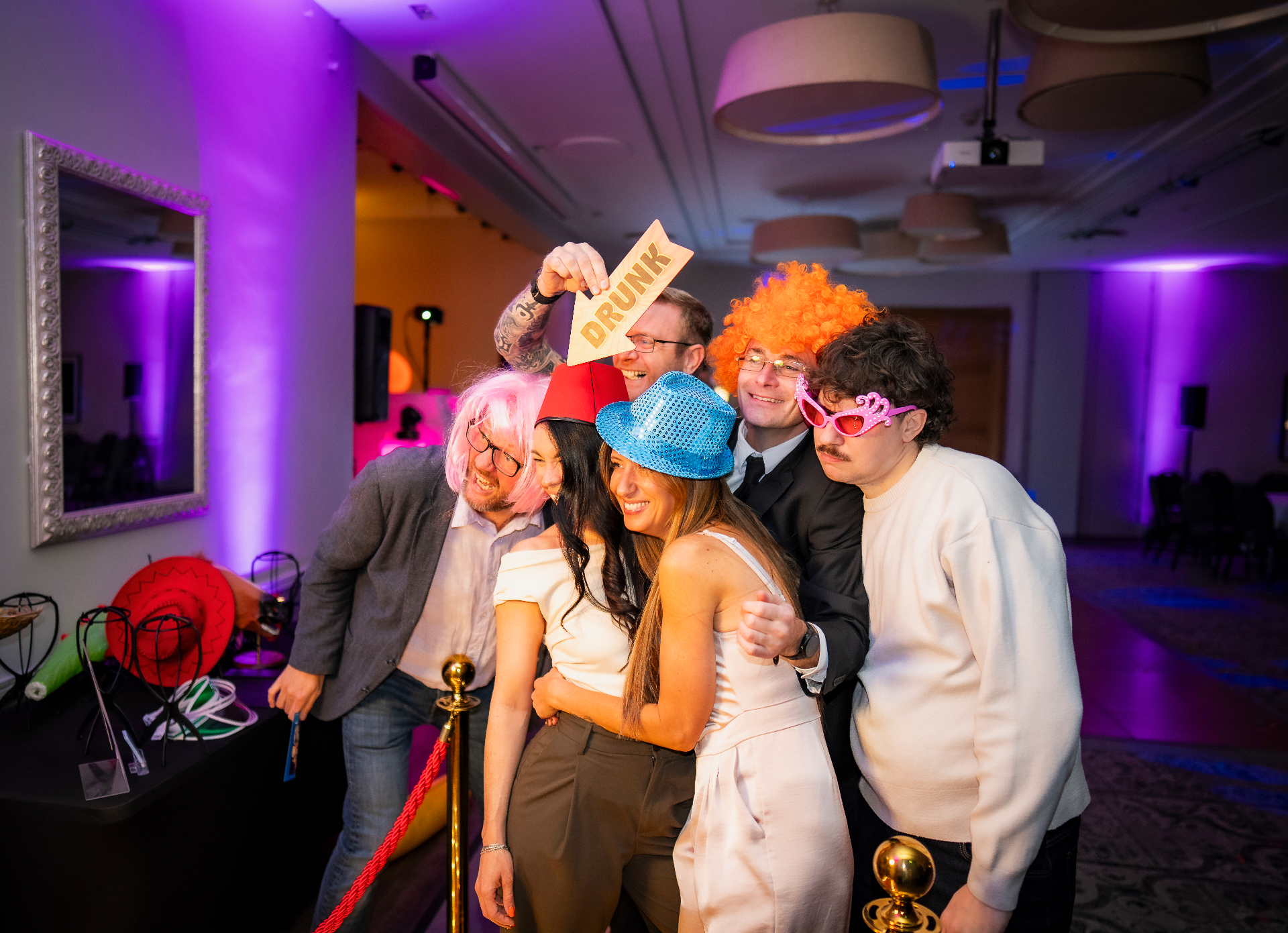 Party guests in wigs, hats and props laughing at the Reflective Collective Co mirror photo booth